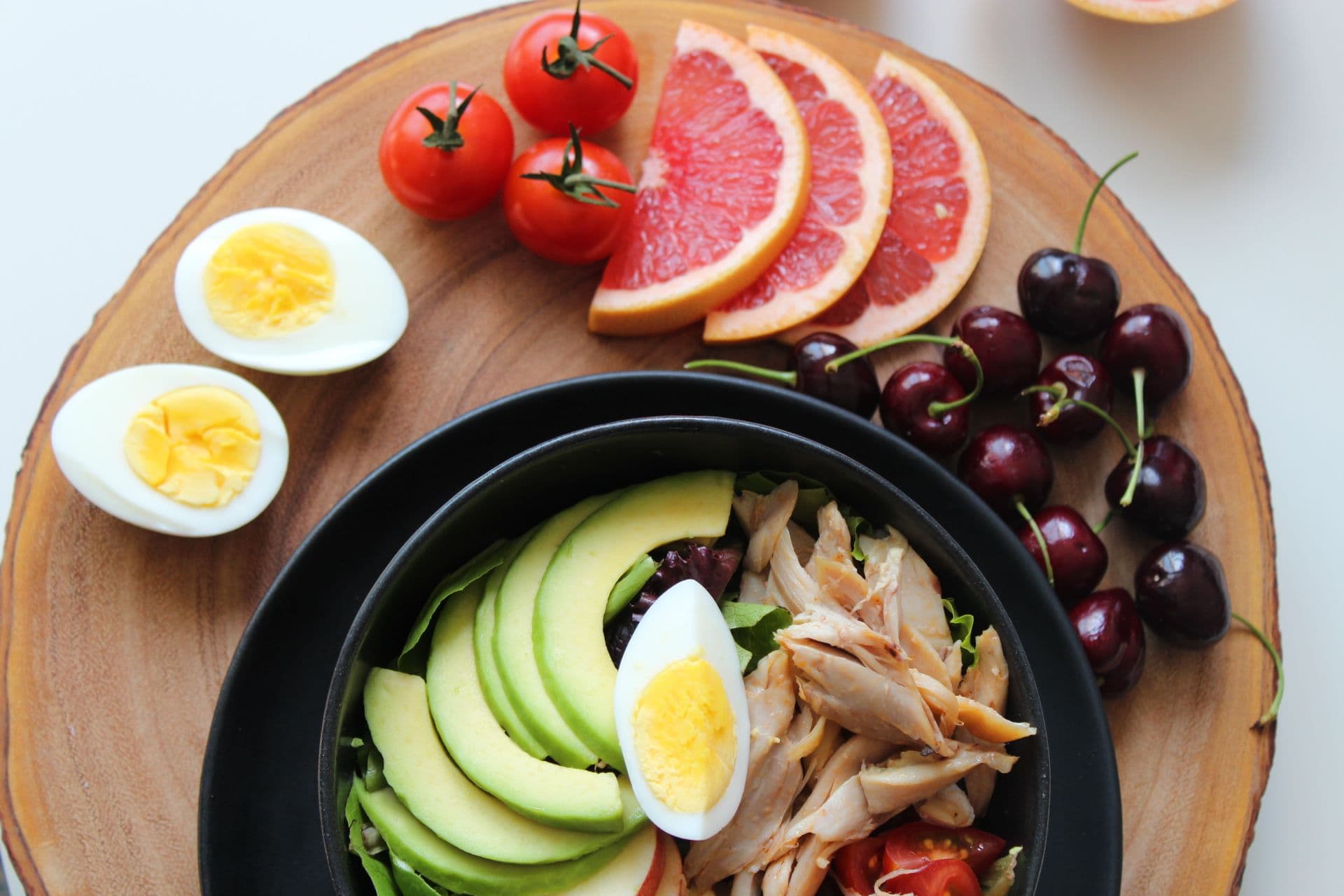 Plato de comida saludable con huevo, aguacate, pollo y fruta fresca